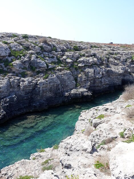 Rock formations by sea against clear sky