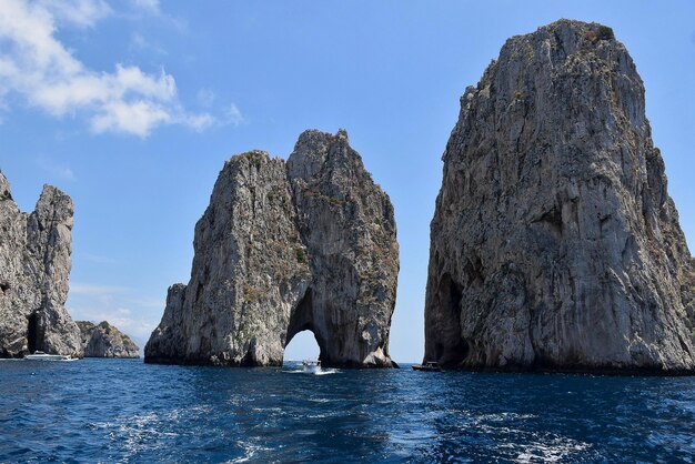 Rock formations in sea against blue sky