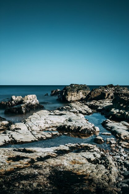 Photo rock formations at shore against clear blue sky