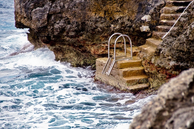 Foto formazioni rocciose spruzzate d'acqua e scale da un mare agitato