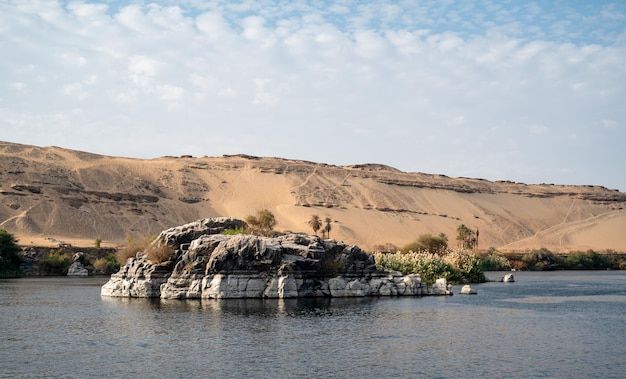 Photo rock in the middle of nile river with the desert in the back egypt