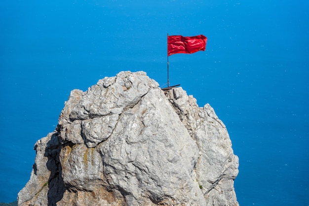 Rock on Mount AiPetri with a red flag over Black Sea Crimea