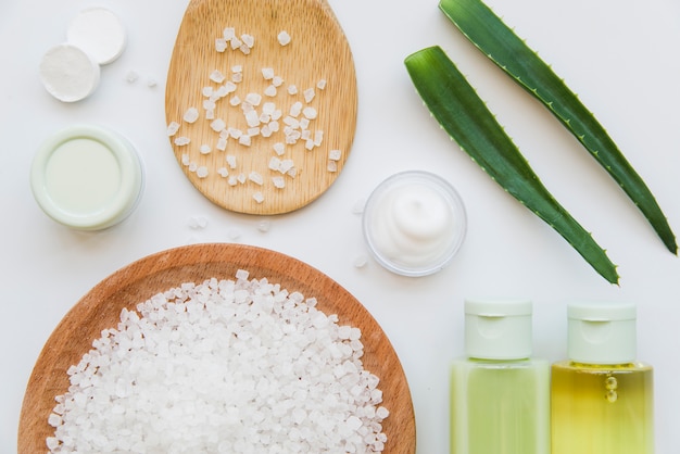 Photo rock salt; spray bottle and cream made with aloevera leaves on white background