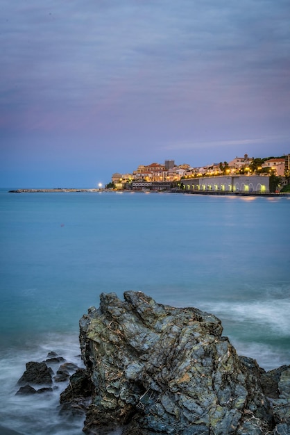 Photo rock at sea shore against sky during sunrise