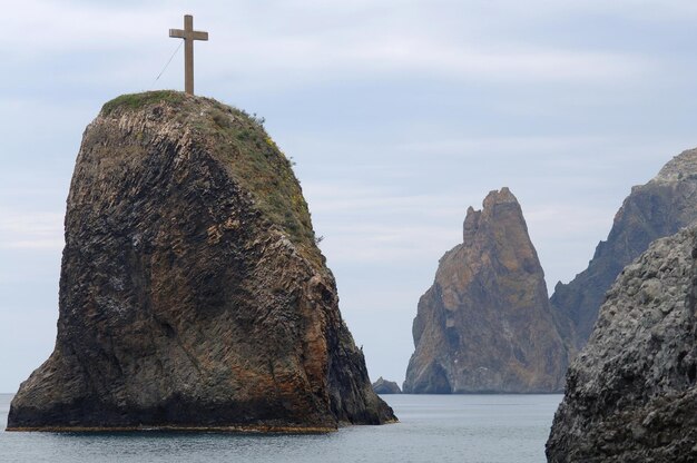 Rock in the sea with a stone cross on top