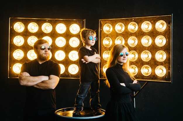 Foto famiglia di rock star. elegante famiglia in abiti neri e occhiali alla luce dei raggi. musica rock-and-roll.