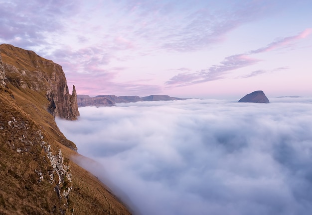 Rock Witchs Finger at sunset Clouds covered the Atlantic Ocean Faroe Islands Aerial view