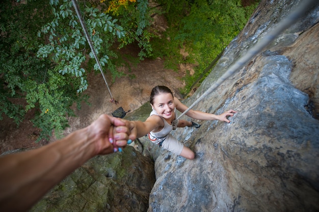 Rockclimber 돕는 산 정상에 도달하는 여성 산악인