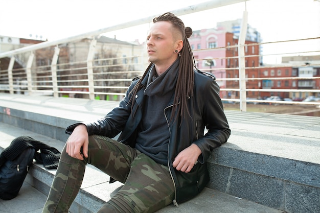 Rocker rock star young man walking on the city street autumn day