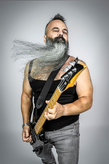 Rocker con chitarra e barba lunga suona con gli occhi chiusi