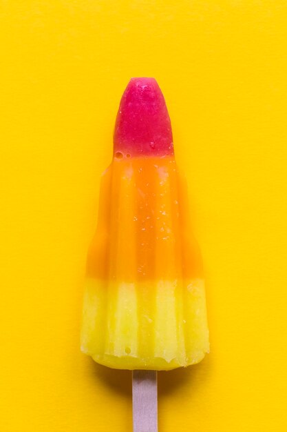 Rocket shaped summer ice lolly on a bright yellow background