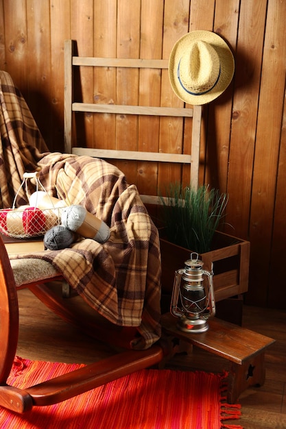 Photo rocking chair with plaid and yarn for knitting near wooden wall