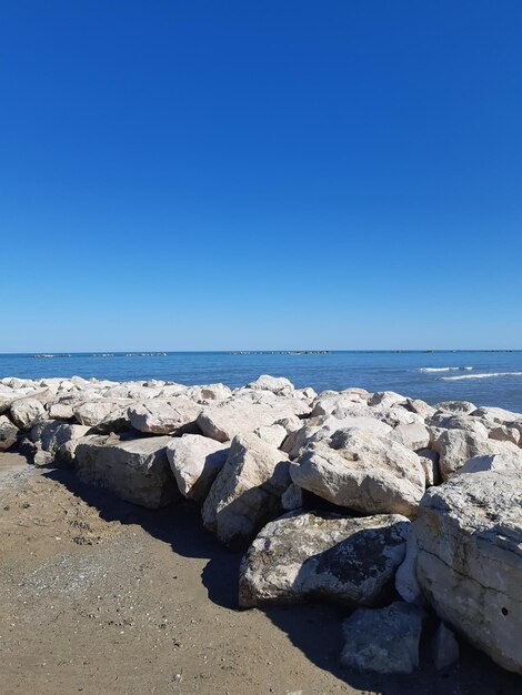 Rocks on beach against clear blue sky