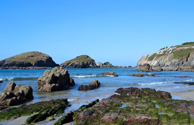 Rocks on beach against clear blue sky