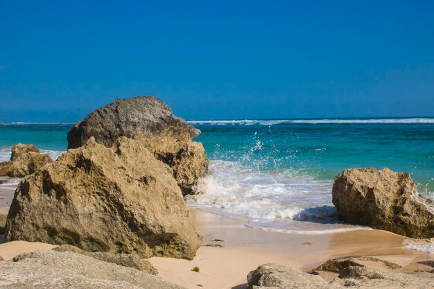 Rocks on beach against clear blue sky