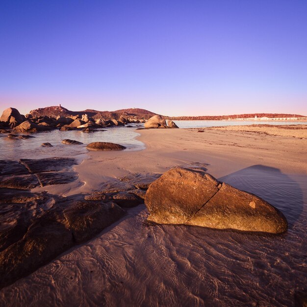 Rocks on beach against clear sky