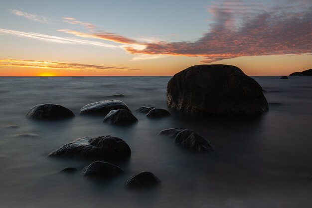 Photo rocks on beach against sky during sunset