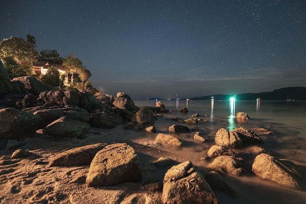 Rocks on the beach with starry and fishing boat in lipe island at night