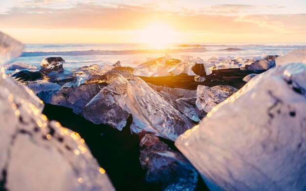 Photo rocks on a beach with the sun setting behind them