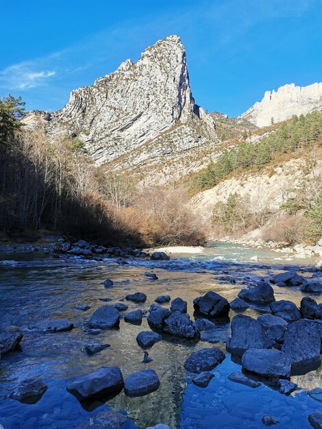 Rocks by lake against blue sky