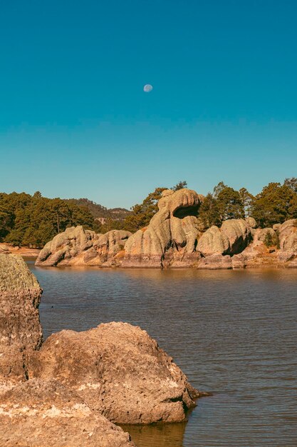 Photo rocks by sea against clear blue sky