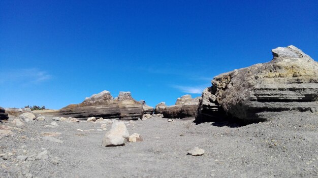 Rocks on landscape against clear blue sky