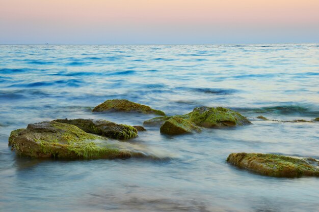 Скалы в море на фоне красивого заката