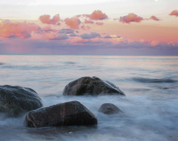 Photo rocks in sea against sky during sunset