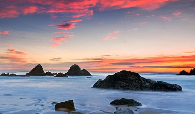 Photo rocks in sea against sky during sunset