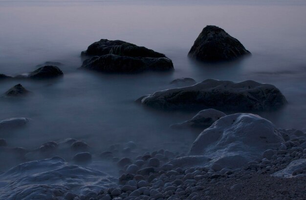 Photo rocks in sea against sky at dusk