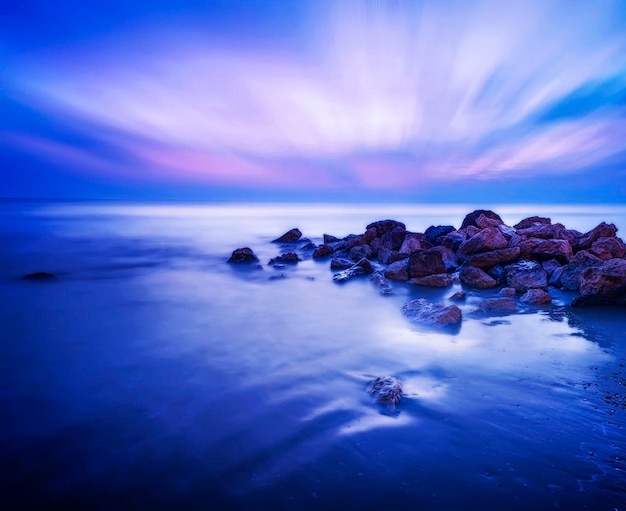 Photo rocks on sea against sky at dusk