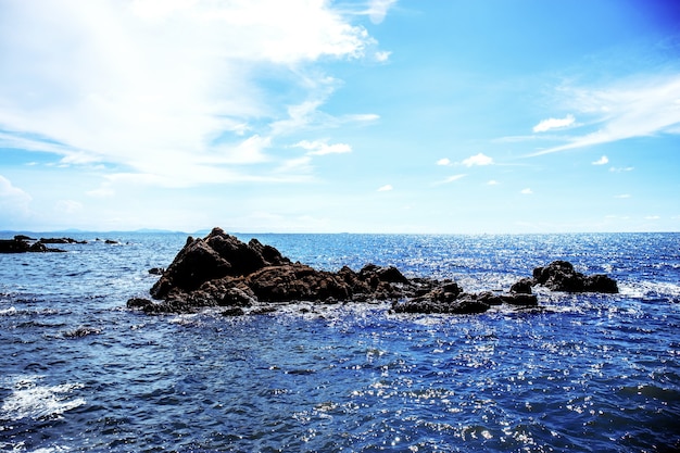 空に日光が差し込む海の岩。