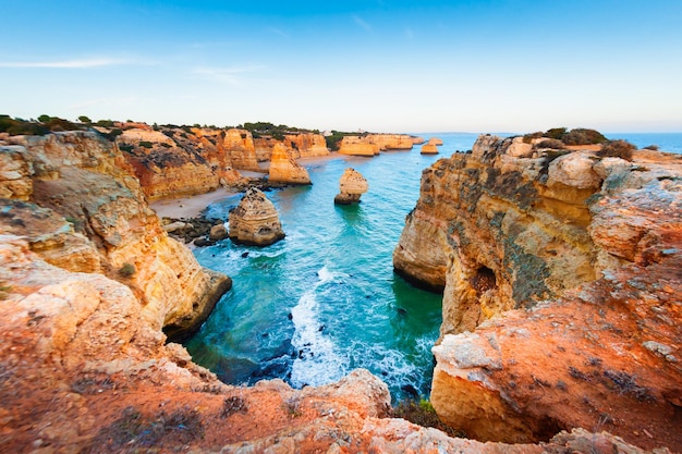 Foto rocce sulla riva dell'oceano atlantico nell'algarve, portogallo paesaggio marino estivo al tramonto