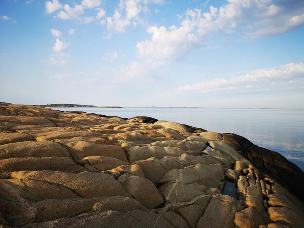 Rocks on shore by sea against sky