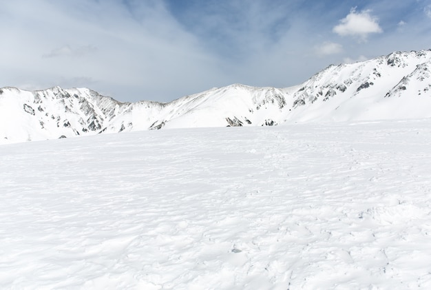 雪の上の岩は青空の下の山を覆った