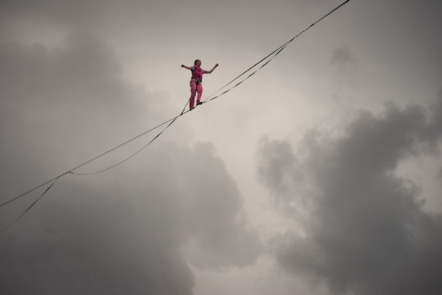 Rocks of a Triangular lake, Russia - August 2, 2021: A rope-walker girl walks along the highline against the background of a dramatic sky