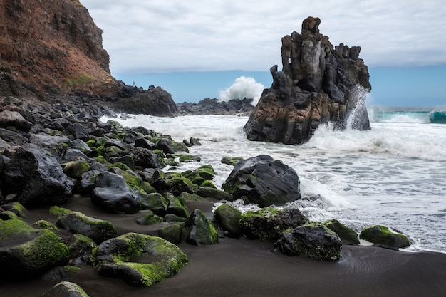 Foto rocce con muschio e mare agitato sulla spiaggia