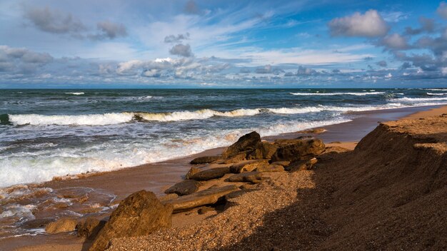 Rocky beach, small waves and blue sky with clouds