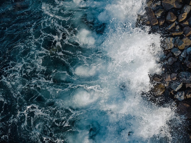 Rocky beach in the south of Tenerife with waves crashing on the beach of volcanic stones