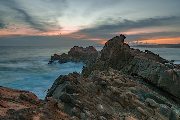 A rocky beach with a sunset in the background