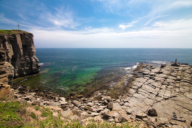 Rocky cape with old lighthouse in one side and  cross on the other