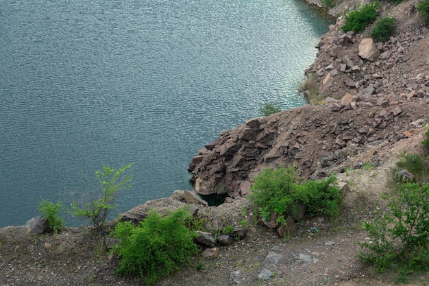 Rocky cliff and lake with dark blue water quarry lakes