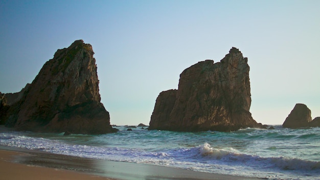 Rocky cliffs rising ocean surface on Portugal Ursa beach summer evening