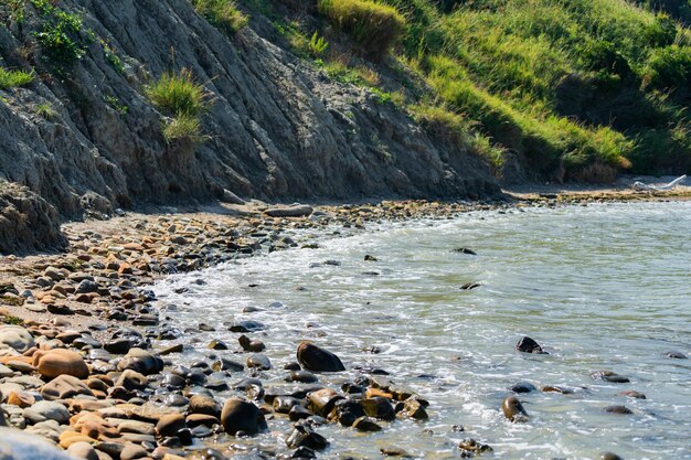 岩の多い海岸線の海の波の背景が海水を壊す岩の多い海岸、リミニの荒いターコイズブルーの水