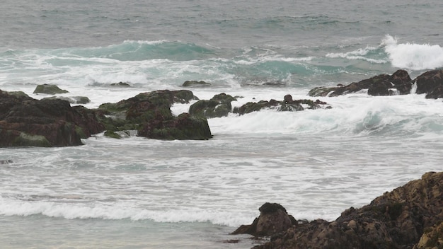 Onde di acqua di mare della costa scoscesa rocciosa dell'oceano che si infrangono sulle rocce monterey california