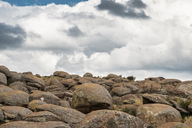 A rocky landscape with a cloudy sky and a white cloud in the background.