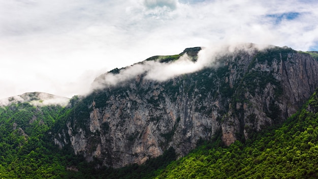 Rocky mountain range with trees and clouds