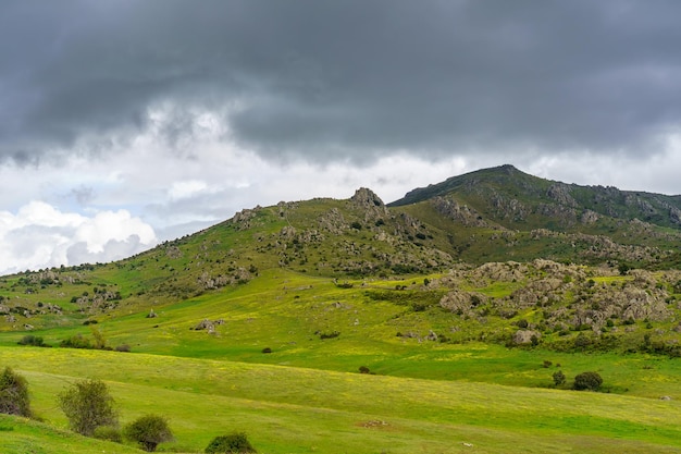 Rocky mountain with black storm clouds and fields of green grass Guadarrama Madrid