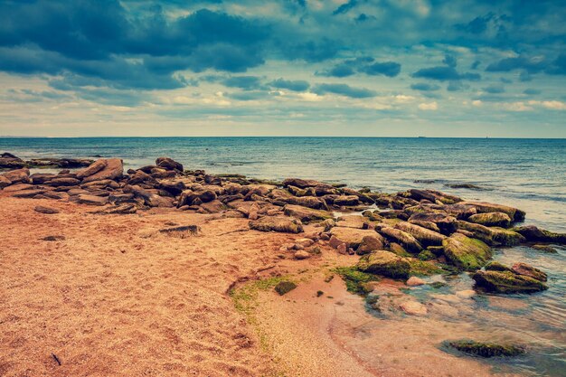 Costa rocciosa del mare con cielo nuvoloso drammatico