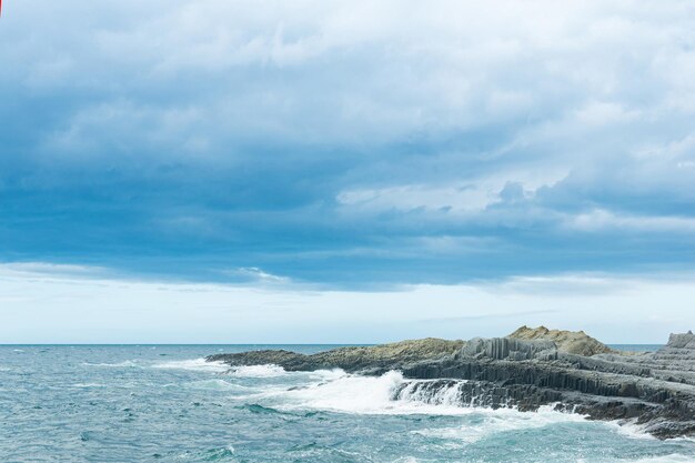 Скалистый берег моря, образованный столбчатым базальтом на фоне бурного морского прибрежного ландшафта Курильских островов